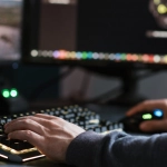 Сотрудник за компьютером в офисе с игровым контентом на экране